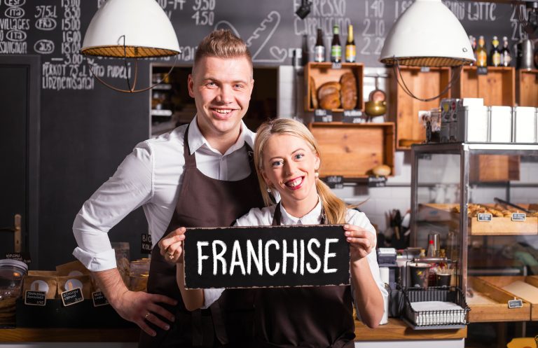Woman and man holding franchise sign in store