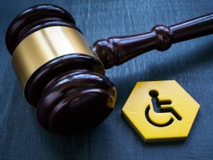 Gavel and Wheelchair icon resting on a blue table.